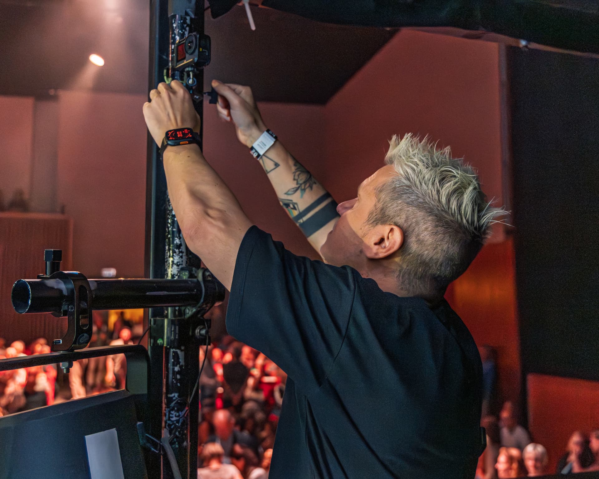 Sam rigging a camera to a stage truss above the crowd