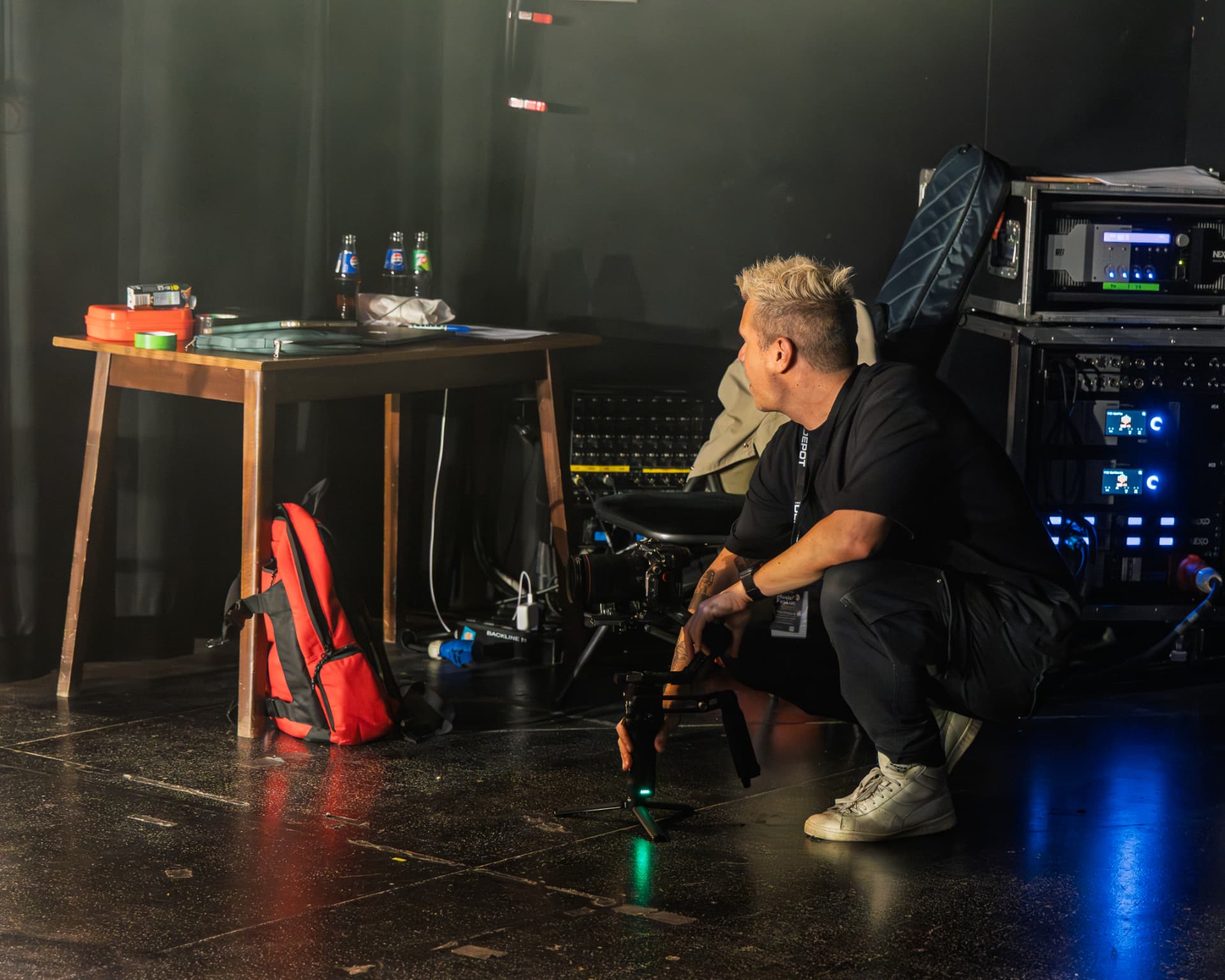 Sam crouching backstage setting up his camera